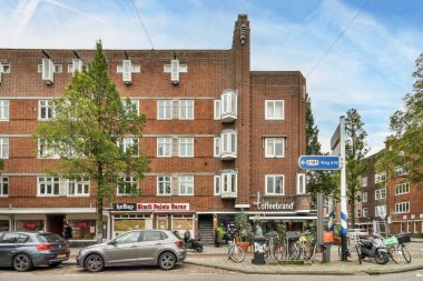 Amsterdam, Hollanda - 10 Nisan 2021: Binanın önüne park edilmiş bir sokak sahnesi ve bazı binaların yanında yürüyen insanlar