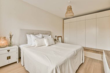 Yatak odası, yatak odası ve beyaz dolaplar yatağın yanında, yatağın üstünde bir lamba var.