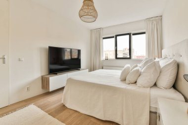 Büyük yataklı bir yatak odası ve yatağın önündeki duvara monte edilmiş bir televizyon.