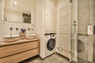 Köşesinde çamaşır makinesi ve kurutma makinesi olan modern bir banyo.