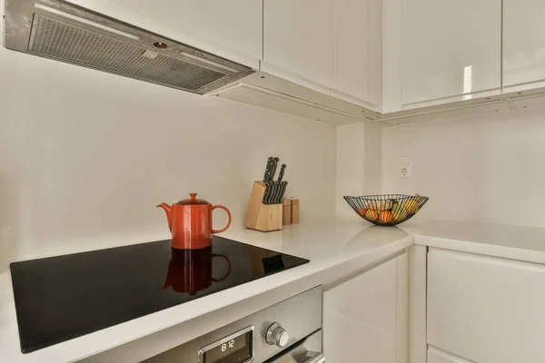 Kuchnia Białymi Szafkami Czarnymi Blatami Środku Obrazu Pomarańczowy Dzbanek Kuchence — Zdjęcie stockowe