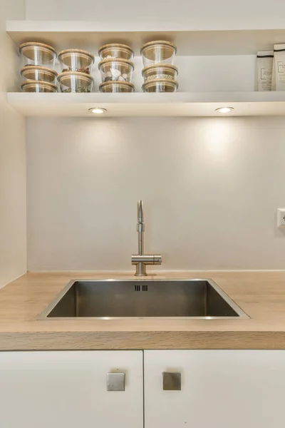 楼上墙上有一个白色橱柜和木制台面的厨房 是一个已经安装好的不锈钢水槽 — 图库照片