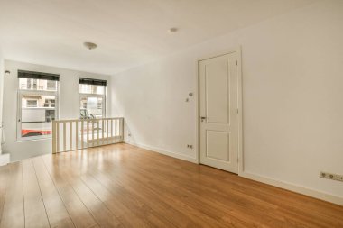 Odasında ahşap döşeme ve beyaz duvarlar olan boş bir oturma odası çok temiz, ama mobilya yok.