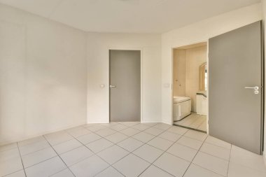 Aynı bölgede başka bir odaya açılan döşemesi ve kapısı olan boş bir oda. Sol tarafta bir tuvalet var.