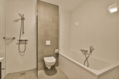 Tuvaleti, duşu ve küveti olan bir banyo duvarın diğer tarafında aynı odada.