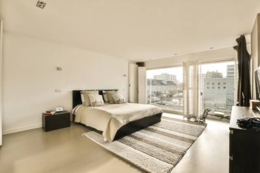 Yatak odası, şifonyer ve televizyon. Pencerenin önünde, sokağa bakıyor.