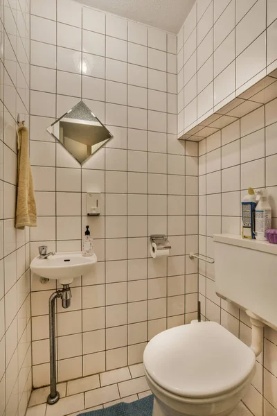 stock image a bathroom with white tiles on the walls and blue rug in front of the toilet bowl, sink and mirror