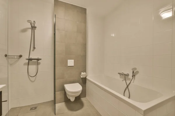在墙的另一边同一间房间里有厕所 淋浴和浴缸的浴室 — 图库照片
