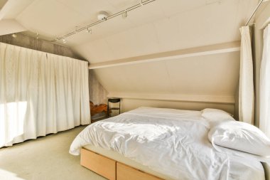 Beyaz çarşaflı bir odada bir yatak ve tavandan arkalarına kadar sarkan perdeler.