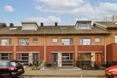 Garaj yolunda arabaları olan bir apartman ve iki katlı evin yanına park edilmiş bir araba.