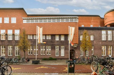 Amsterdam, Hollanda - 10 Nisan 2021: Önünde ve yanındaki kaldırımda birçok bisikletin park ettiği tuğla bir yangın musluğu var.