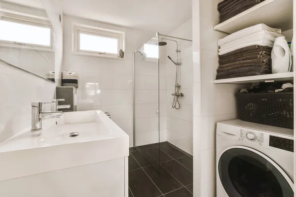 a laundry room with a washer, dryer and towels on the shelf in front of the washing machine
