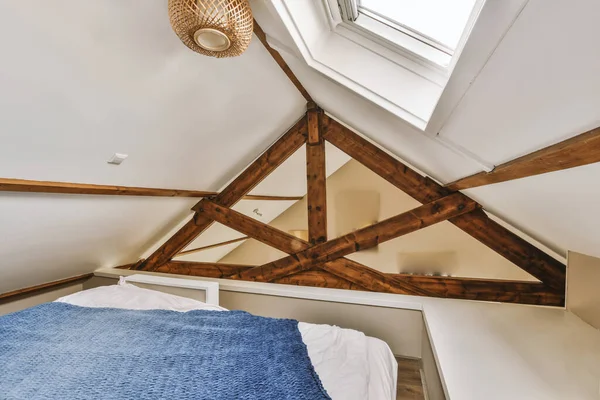 a bed in a room with wood beams on the walls and ceiling above it is a window that looks out to the outside