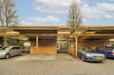 İki araba bir evin önüne park edilmiş ve çatısı garaja asılmış.