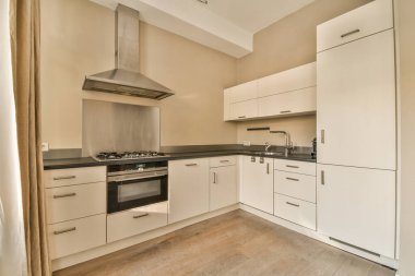 Tezgahların üzerinde beyaz dolaplar ve siyah tezgahlar olan bir mutfak iç mekandan alınmıştır.