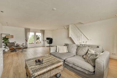 İkinci kata çıkan merdivenin önünde kanepesi ve sehpası olan bir oturma odası.