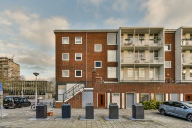 Amsterdam, Hollanda - 10 Nisan 2021: Otoparkın yanına park edilmiş bir apartman ve sokağın her iki tarafında da bazı binalar