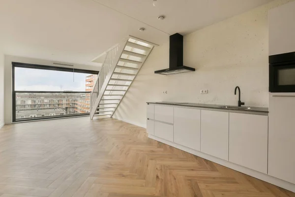 Uma Cozinha Escadas Uma Sala Com Piso Madeira Armários Brancos — Fotografia de Stock