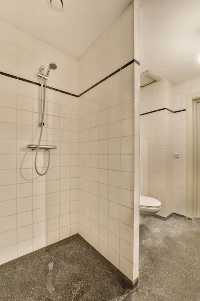 壁に白いタイルのバスルームとシャワーヘッドの周りの黒いトリム壁に取り付けられています — ストック写真