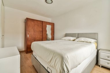 a bedroom with a bed, dresser and mirror on the wall in front of the bed is an empty room