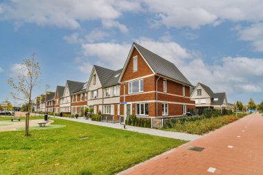 Güneşli bir günde bir sıra ev mavi gökyüzü ve beyaz bulutlar dışarıdan çekiliyor.