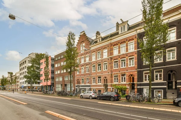 stock image a city street with cars parked on the side and buildings in the middle part of the street, all bricked up