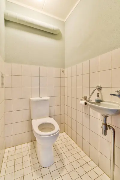横の角に白いタイルとトイレのあるバスルームはシンクで壁に面しています — ストック写真