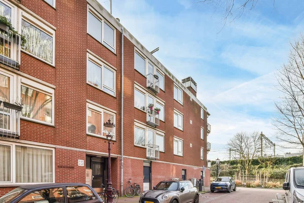 アムステルダム オランダ 2021 いくつかの車は多くの窓やボールを持つアパートの建物の前の道路の側に止め — ストック写真