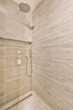 Duvarlarında fayans olan bir banyo ve duvara monte edilmiş duş başlığı, temiz ve kullanıma hazır.