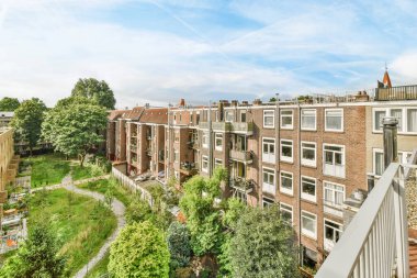 Amsterdam, Hollanda - 10 Nisan 2021: Önünde bir sürü ağaç ve çalılık olan bir apartman dairesi - emlakçılar web sitesinden görüntü nezaketi