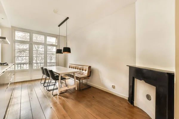 stock image an empty living room with wood flooring and a fire place in the middle of the room, there is a small dining table