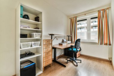 Masası, sandalyesi ve kitaplığı açık bir pencerenin önünde olan bir oda.