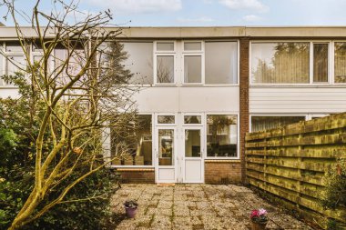 Ön bahçesinde ağaçlar ve çalılar olan bir evin dış görünüşü, sokak tarafından görüldüğü gibi.