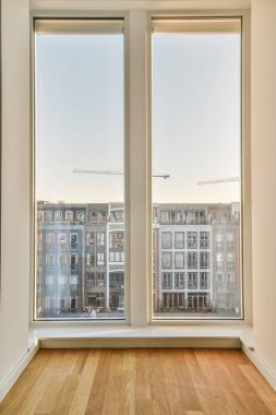 boş bir oda ahşap zemin ve geniş pencereler şehir manzarasına içeriden bakıyor.