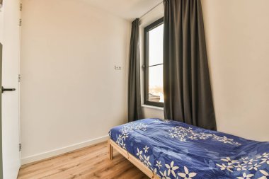 Bir yatak odası, bir yatak odası ve köşesinde de bir pencere, içinden hiç ışık geçmediğini gösteriyor.