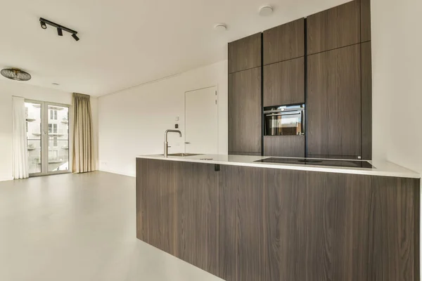一个现代化的厨房 有木柜和白色的台面在图像的中心是一个开放的客厅 — 图库照片