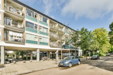 Amsterdam, Hollanda - 10 Nisan 2021: Önünde arabaların park ettiği bir apartman ve her iki tarafında ağaçlar olan bir apartman.
