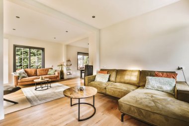 Odanın ortasında kanepeleri ve kahve masası olan bir oturma odası var. Başka bir odaya açılan açık bir kapı var.