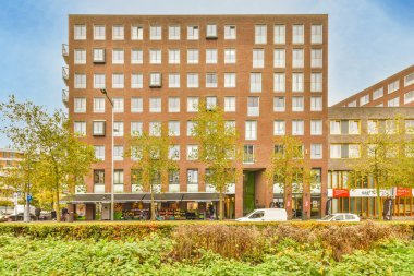 Önünde çok sayıda pencere ve bitki bulunan ve yüksek tuğla binalarla çevrili bir bina.