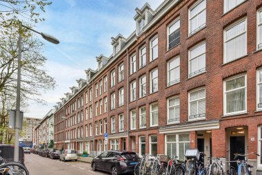 Amsterdam, Hollanda - 10 Nisan 2021: Bazı bisikletler pencere ve balyaları olan tuğla binaların önüne park etmiş.