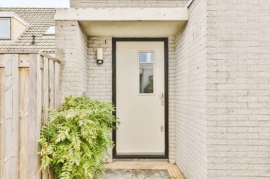 Kapısı ve ön bahçesinde bitkiler olan bir ev dışarıdan girişe bakıyor.