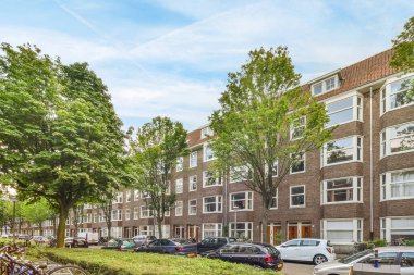 Amsterdam, Hollanda - 10 Nisan 2021: Park etmiş arabaların ve bisikletlerin bulunduğu bir şehir caddesi Apartman binalarının önündeki kaldırımda, Amsterdam, Hollanda stok fotoğrafı