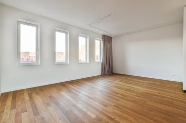 an empty room with wood flooring and large windows looking out onto the street in front of the apartment building
