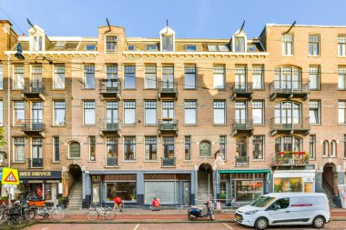 Amsterdam, Hollanda - 10 Nisan 2021: bitişiğinde bisikletleri olan bir apartman ve arkalarında yürüyen insanlar
