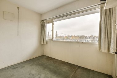 Duvarda ya da zeminde kimse olmayan boş bir oda ve şehre bakan bir pencere var.