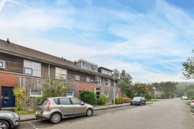 Amsterdam, Hollanda - 10 Nisan 2021: yan tarafında arabalar ve arka tarafında evler olan bir cadde, bazı insanlar yolda yürüyor