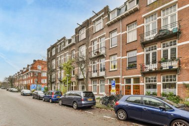 Amsterdam, Hollanda - 10 Nisan 2021: bazı arabalar cadde kenarına park edilmiş, üzerinde pencere ve balyalar olan binaların önünde.,
