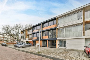 Binanın önüne park etmiş arabalarla dolu bir apartman kompleksi ve iki katlı çok katlı aile evleri.