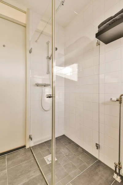 壁にタイルの床と白いタイルのシャワールーム壁の角に鏡があります — ストック写真