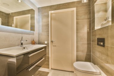 Tuvaleti, lavabosu ve aynası olan bir banyo fotoğrafta yan yana duruyor.